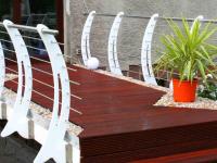 Schmale Terrasse mit dunklen Dielen und weißem Geländer 